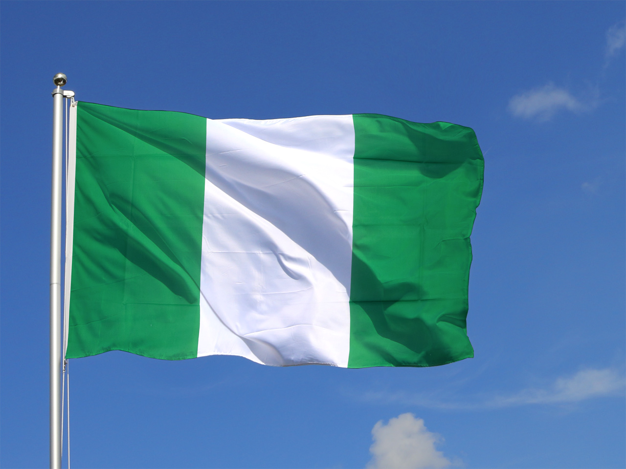 The Nigerian flag flying against a clear sky